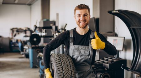 Car mechanic changing wheels in car